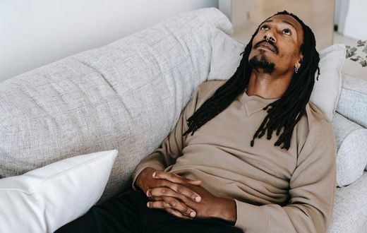 Pensive black man lying on couch [Photo: Alex Green]
