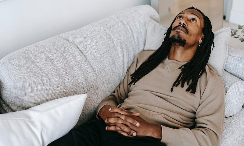 Pensive black man lying on couch [Photo: Alex Green]