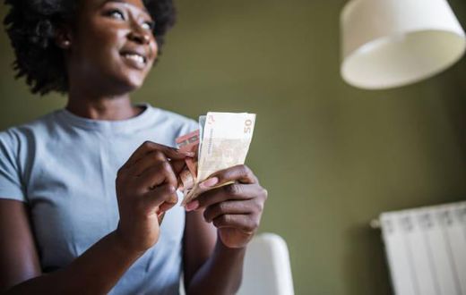 A woman at home counting money. Photo credits: Riska