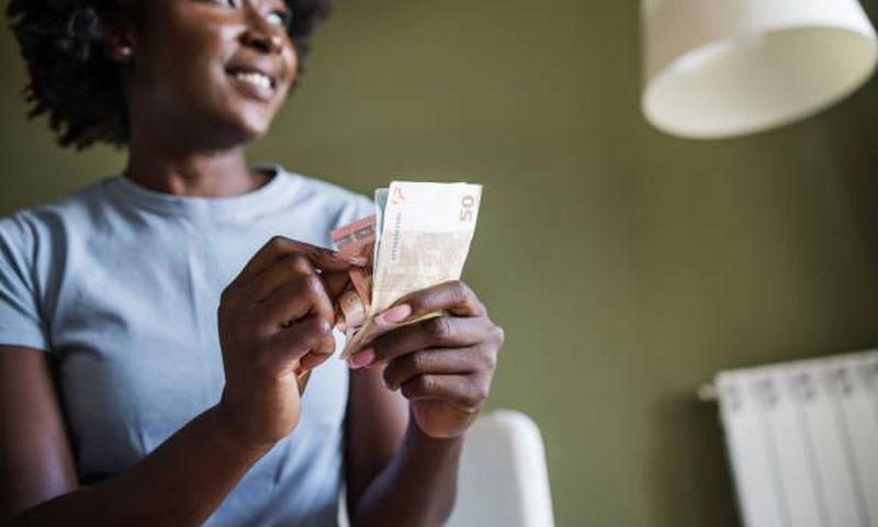 A woman at home counting money. Photo credits: Riska