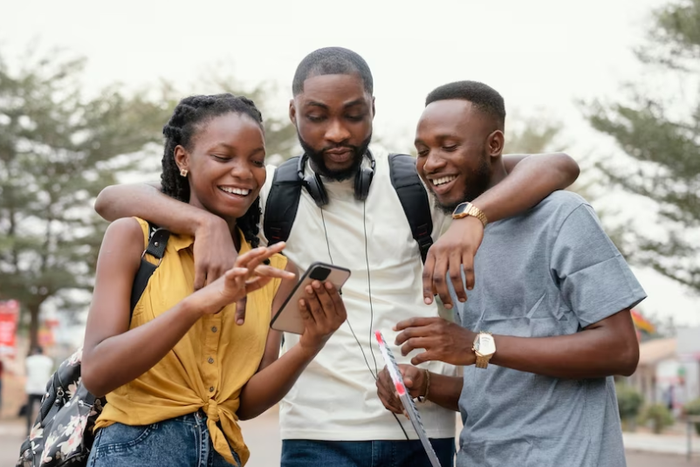 A group of black people checking out a phone [Freepik]