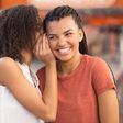 Black girl whispering secret to smiling girlfriend [Freepik]