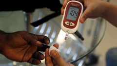 A paramedic checking the blood sugar levels of a diabetes patient.