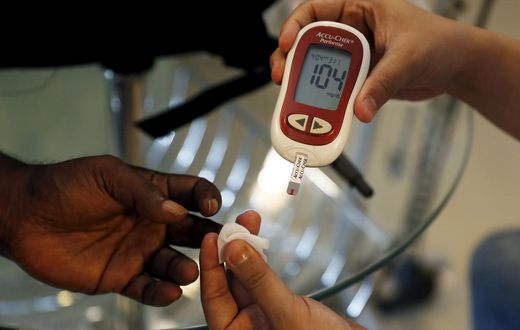 A paramedic checking the blood sugar levels of a diabetes patient.