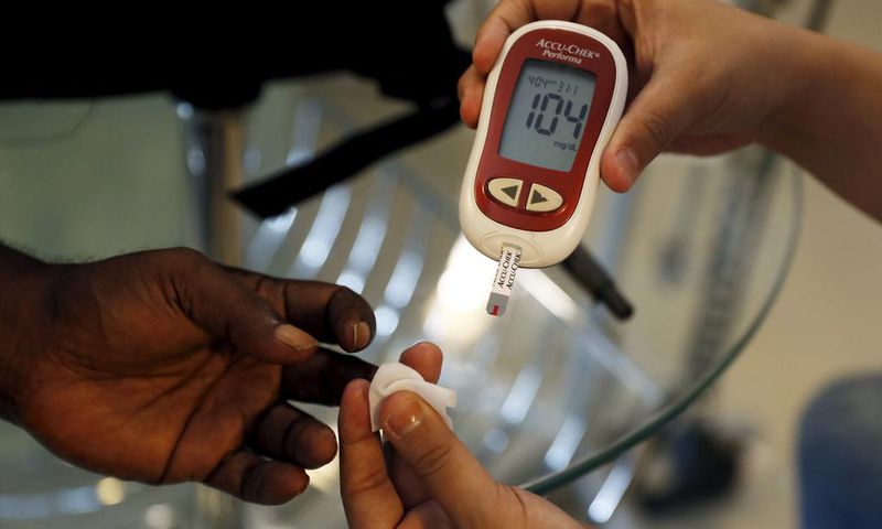 A paramedic checking the blood sugar levels of a diabetes patient.