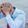Concentrated black man grabbing head with hands sitting at table [Photo: Nicola Barts]
