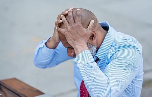 Concentrated black man grabbing head with hands sitting at table [Photo: Nicola Barts]