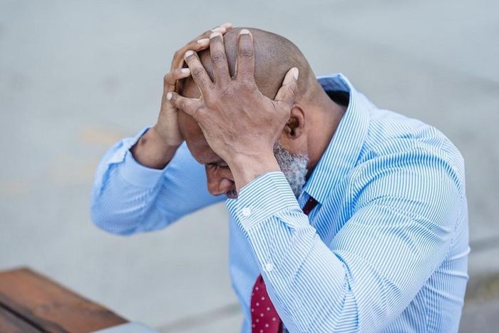 Concentrated black man grabbing head with hands sitting at table [Photo: Nicola Barts]