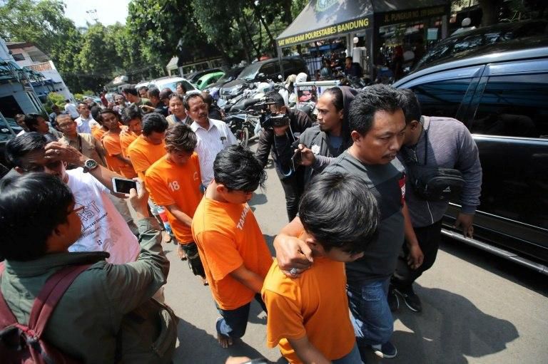 Indonesian policemen escort eight suspects in the beating to death of a rival football fan