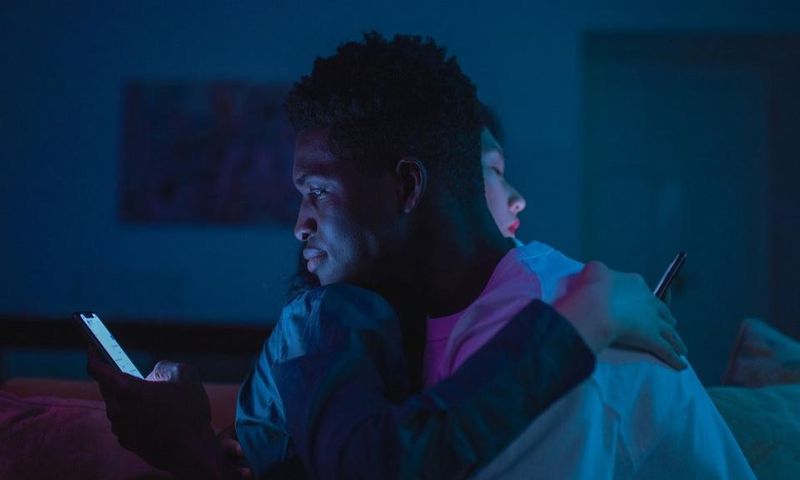 Couple using their phones while hugging [Photo: Cottonbro Studio]