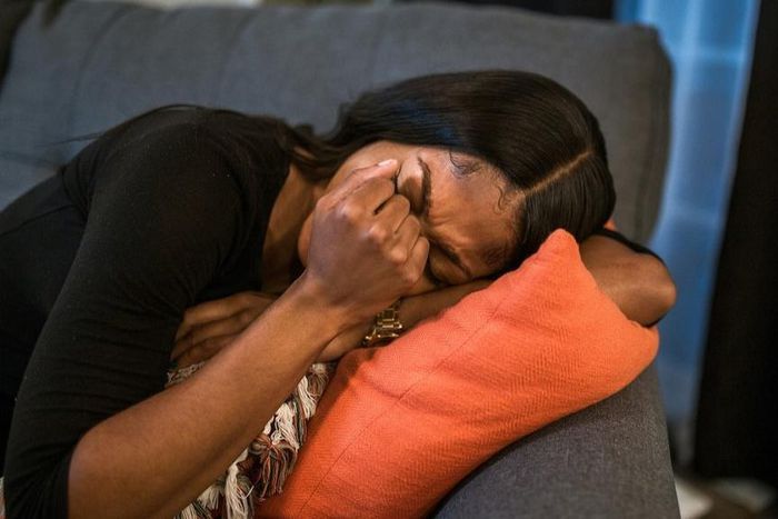 Sad woman in black shirt lying on pillow on a sofa [Photo: RDNE Stock Project]