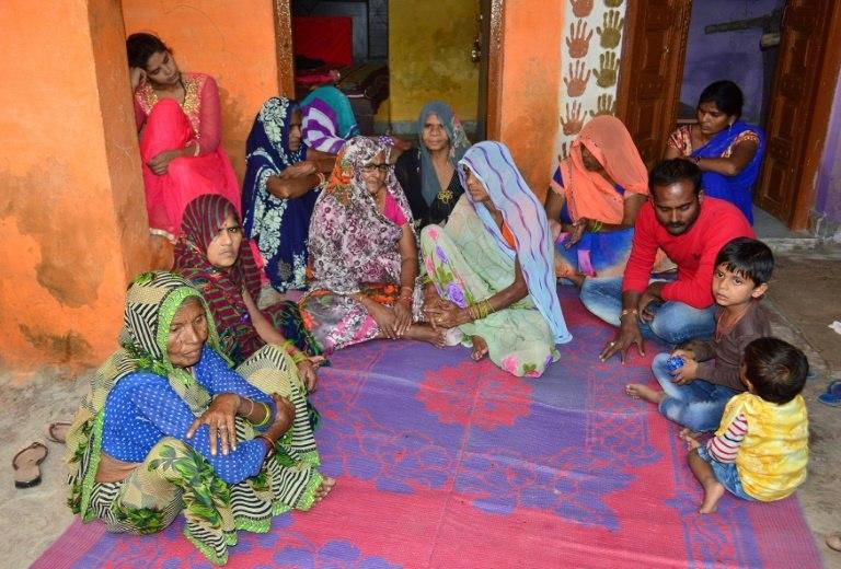 The Indian father (3rd R, in red) of a baby who police say was killed by a macaques monkey sits with relatives at their family home in Agra on November 15, 2018