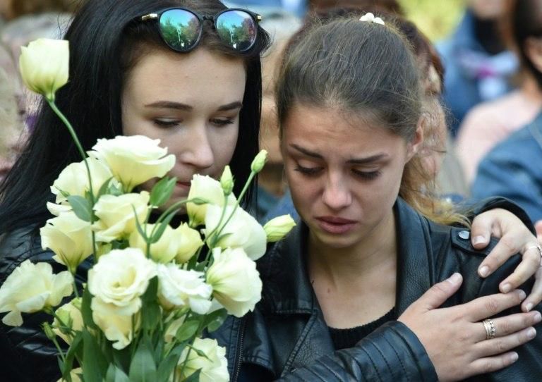 Two girls attend a church service for the victims of a college attack in Kerch, Crimea