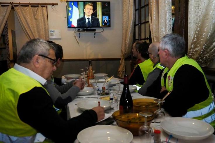 'Yellow vest' protestors take notes as they watch French President Emmanuel Macron's speech on television