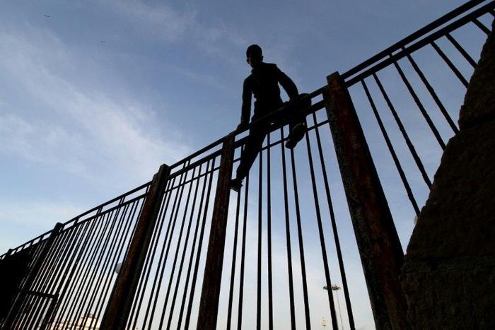 A Moroccan young boy climbs a fence in the port of the Spanish enclave of Melilla bordering Morocco on May 16, 2017.Midnight in Melilla and hidden near the harbor, nine-year-old Wahib is one of many children willing to do the "riski": take all the risk...