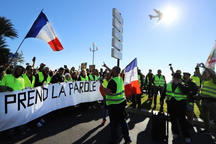 Protestors hold a banner reading "The people speak out" during a protest of 'yellow vests' against rising fuel prices and living costs, in the southern French city of Nice on December 8, 2018