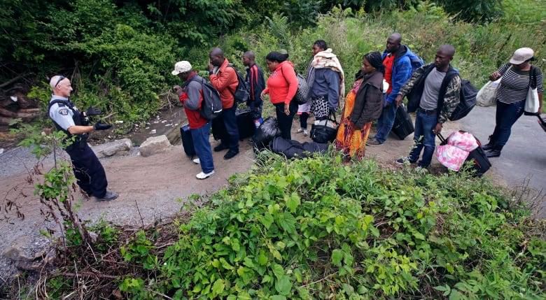 A Royal Canadian Mounted Police officer informs migrants of their rights at the Saint-Bernard-de-Lacolle border, on August 7, 2017