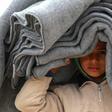 A Syrian displaced boy carries blankets over his head inside the Internallly Displaced Persons (IDP) camp of Al-Hol in northeast Syria