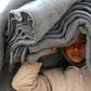 A Syrian displaced boy carries blankets over his head inside the Internallly Displaced Persons (IDP) camp of Al-Hol in northeast Syria