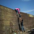 A group of Central American migrants climb the border fence between Mexico and the United States near El Chaparral border crossing in Tijuana -- the crisis is ongoing