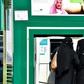 Saudi women withdraw money from an automatic teller machine along a main street in the capital Riyadh on December 18, 2018