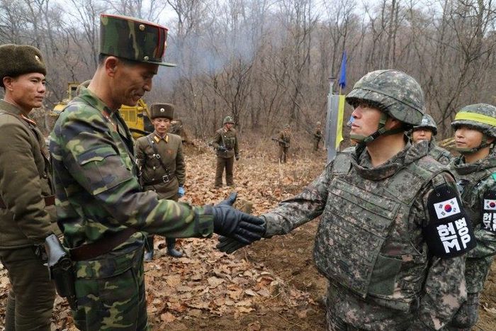 Pictures handed out by Seoul's defence ministry Thursday showed a South Korean soldier and a North Korean counterpart taking part in the "recent" roadworks holding their hands out toward each other, with their colleagues watching