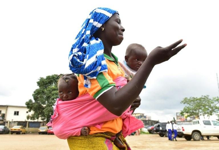 A woman dances with twin baby brothers during the Twins Day celebration in Abidjan