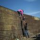 Central American migrants climb the border fence between Mexico and the United States in Tijuana, Mexico
