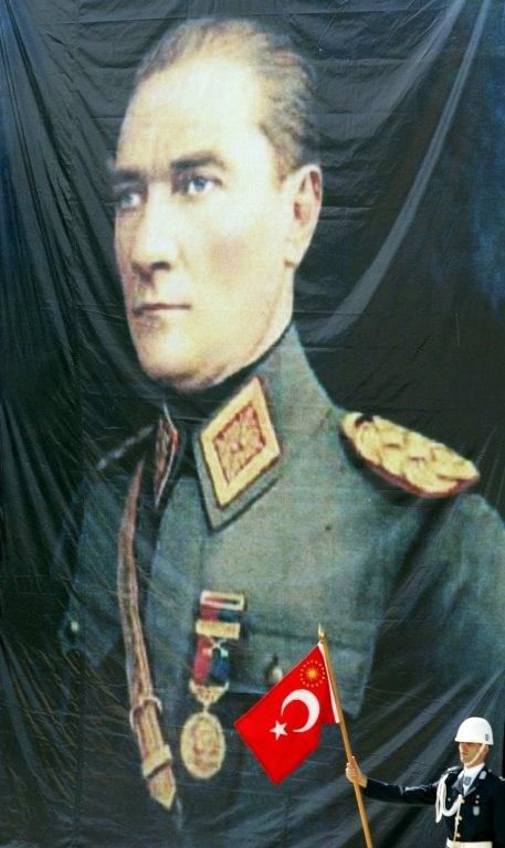 A cadet with a Turkish flag in front of a portrait of Mustafa Kemal Ataturk at an Air Force Academy graduation ceremony in 2007