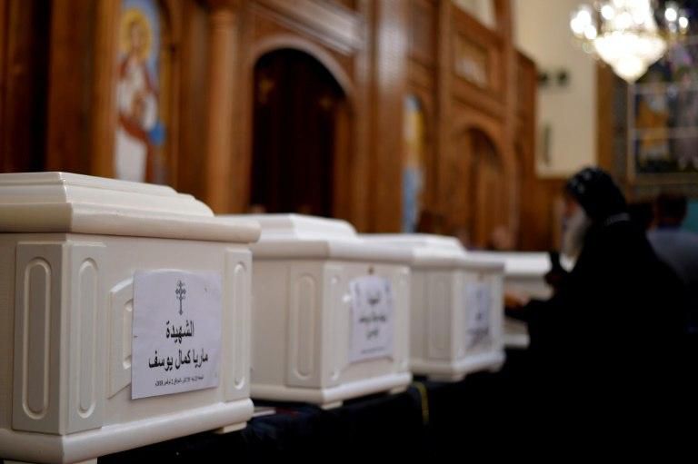 An Coptic priest blesses the coffins of victims of an attack claimed by the Islamic State group, during an early morning ceremony at a church in Egypt's Minya province on November 3, 2018