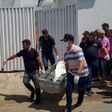 Forensic experts carry a corpse to be transported to the morgue after an attempted bank robbery in Milagres, Ceara state, Brazil