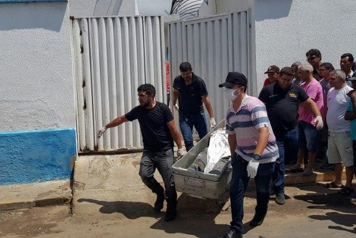 Forensic experts carry a corpse to be transported to the morgue after an attempted bank robbery in Milagres, Ceara state, Brazil