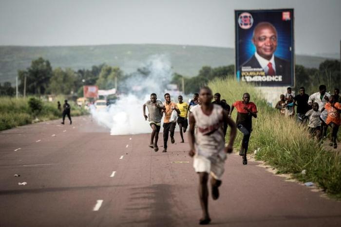 Supporters of Democratic Republic of Congo opposition leader Martin Fayulu run as police teargas fills on December 19, 2018 in Kinshasa, after a demonstration