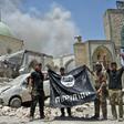In this file photo taken on June 30, 2017 a member of Iraq's counter-terrorism squad flashes a victory sign as others hold upside-down an Islamic State group flag outside Al-Nuri Mosque in Mosul's Old City after IS was ousted from the area