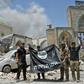 In this file photo taken on June 30, 2017 a member of Iraq's counter-terrorism squad flashes a victory sign as others hold upside-down an Islamic State group flag outside Al-Nuri Mosque in Mosul's Old City after IS was ousted from the area