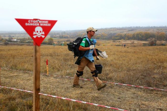 The pine-fringed village's former pasture is cordoned off and marked by signs reading "Danger, mines" in English