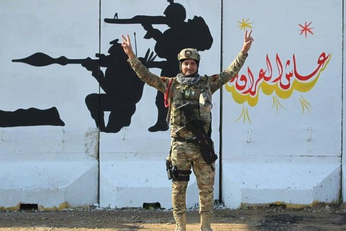 A member of Iraq's Rapid Response military unit poses in front of a mural glorifying Iraqi forces