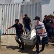 Forensic experts carry a corpse to be transported to the morgue after an attempted bank robbery in Milagres, Ceara state, Brazil