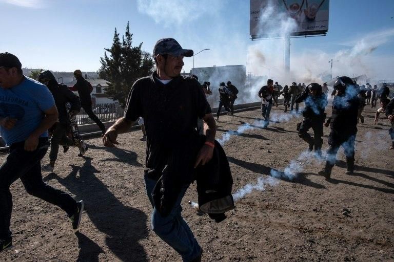 Central American migrants -- mostly Hondurans -- run along the Tijuana River near the El Chaparral border crossing in Tijuana after the US border patrol threw tear gas to disperse them in late November 2018
