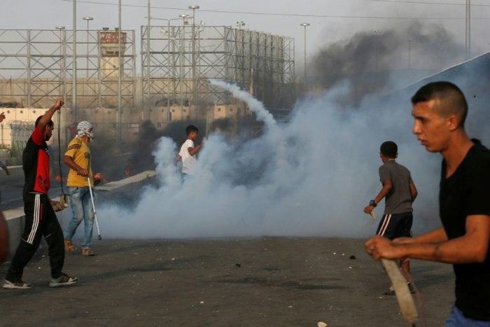 Palestinian protesters demonstrate amid tear gas fired by Israeli troops at the Erez border crossing with Israel in the northern Gaza Strip on October 3, 2018