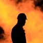 An unidentified oil worker walks in front of a natural gas flame burning off in the Persian Gulf desert oil field of Sakhir, Bahrain.