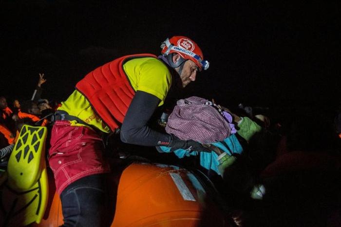 A member of Proactiva Open Arms organisation holds a new born baby rescued with her mother