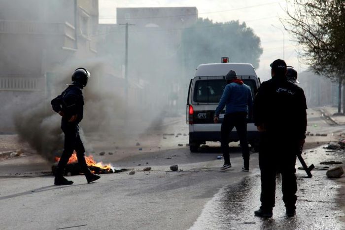 Tunisian policemen stand watch during a demonstration in the city of Kasserine on December 25, 2018