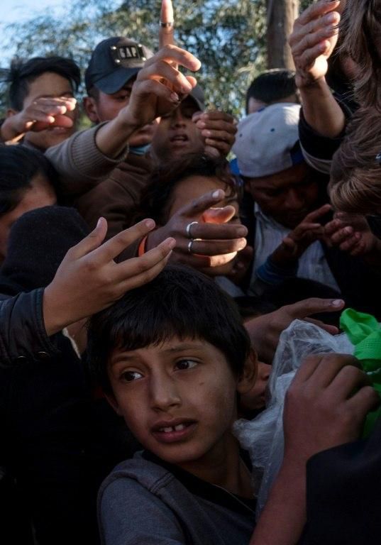 Central American migrants struggle for fruit given by volunteers outside a temporary shelter in Tijuana, Mexico, on the US border