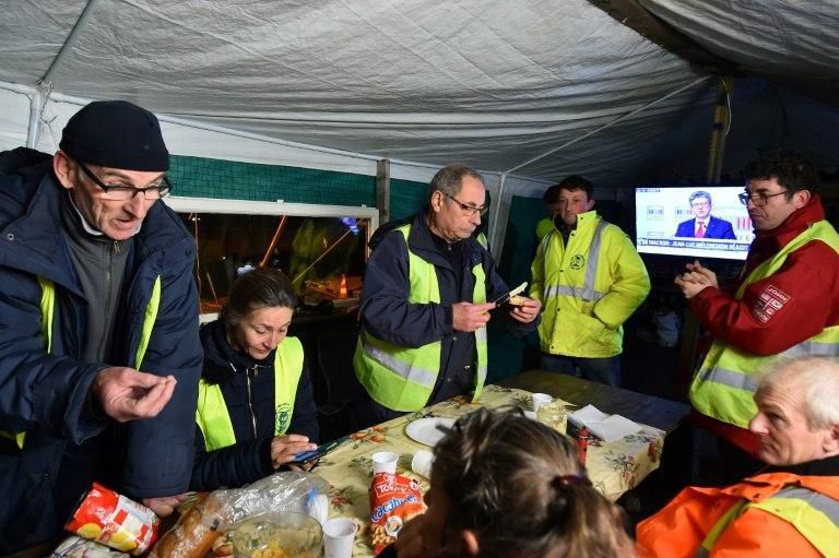 After listening to Macron's speech, protestors watch leftist Jean-Luc Melenchon talking on TV under a tent in Montabon, near Le Mans