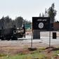 A burnt-out vehicle is seen next to the Islamic State group's flag on the outskirts of the Syrian city of Raqa on June 11, 2017