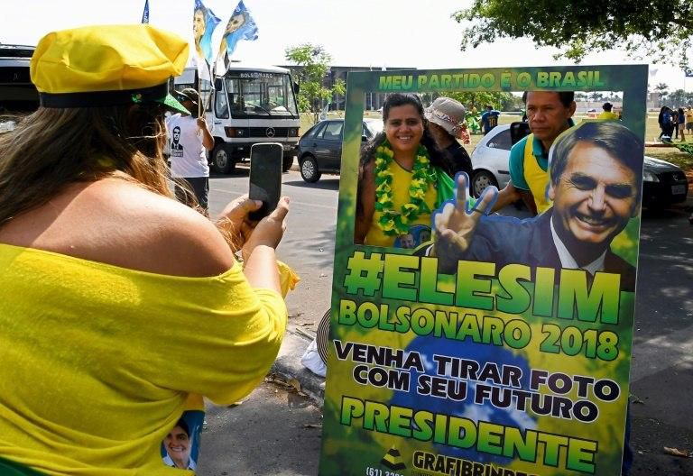 A supporter of Brazil?s far-right presidential candidate Jair Bolsonaro takes a snapshot with a campaign sign in Brasilia