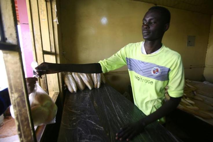 A Sudanese man hands a bag of bread to a customer at a bakery in the capital Khartoum on January 5, 2018