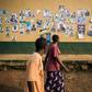 A man and a woman walk past a wall covered with electoral posters in Beni on December 21, 2018