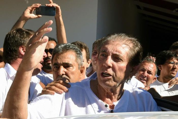 Brazilian "spiritual healer" Joao Teixeira de Faria (C), known as "Joao de Deus" (John of God) is escorted by supporters upon arrival at his "healing center" southwest of Brasilia